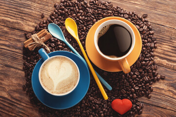 blue and yellow cups of coffee,  spoons, beans and heart on a wooden background Coffee is the good...