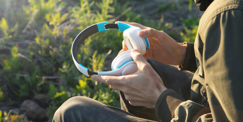 Caucasian man holding headphones at outdoor.