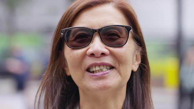 Portrait of senior Asian female talking cheerfully to camera 