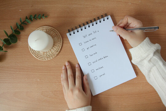 Text list for self care on notebook with pen on white background, office desk.