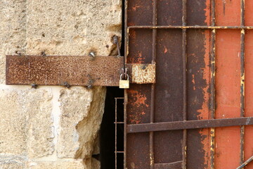 An iron padlock hangs on a closed gate