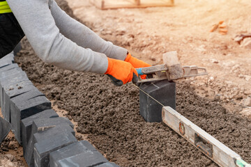 Builder installing paving blocks during road and footpath construction on semi-dray concrete mix