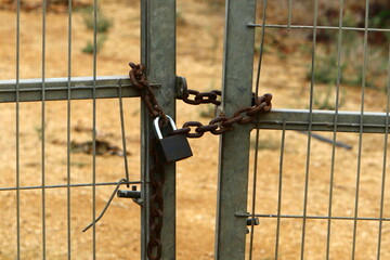 An iron padlock hangs on a closed gate