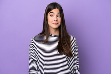 Young Brazilian woman isolated on purple background making doubts gesture looking side