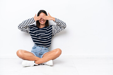 Young caucasian woman sitting on the floor isolated on white background covering eyes by hands