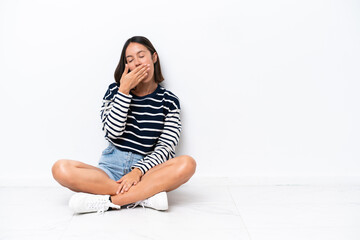 Young caucasian woman sitting on the floor isolated on white background yawning and covering wide...