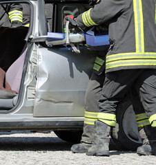 firefighters who with a powerful hydraulic shear open the car damaged after the road crash