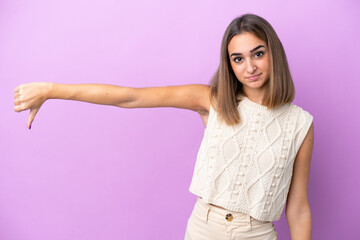 Young caucasian woman isolated on purple background showing thumb down with negative expression