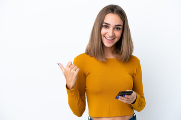 Young caucasian woman isolated on white background using mobile phone and pointing to the lateral