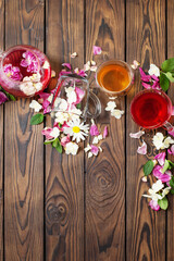 various teas with herbs and flowers on a dark wooden table, top view