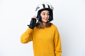 Young caucasian woman with a motorcycle helmet isolated on white background listening to something by putting hand on the ear