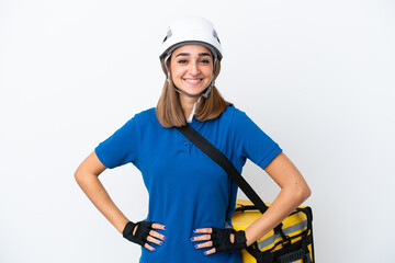 Young caucasian woman with thermal backpack isolated on white background posing with arms at hip and smiling