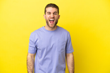 Handsome blonde man over isolated yellow background shouting to the front with mouth wide open