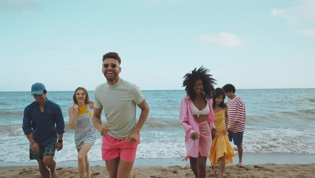 roup of friends having fun on the beach. Multiethnic Teenagers having a good time during the summer celebrating together next to the ocean.