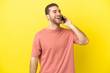 Handsome blonde man using mobile phone over isolated background laughing