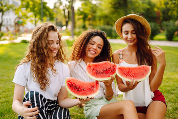 Three  young woman have fun together and eating watermelon in hot summer day. People, lifestyle, travel, nature and vacations concept. 