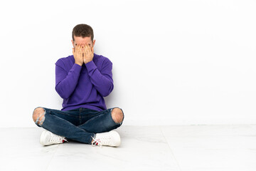 Young man sitting on the floor with tired and sick expression