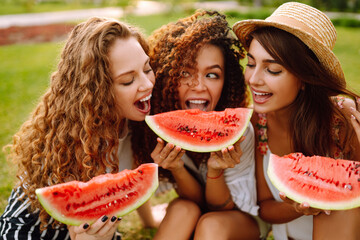 Three  young woman have fun together and eating watermelon in hot summer day. People, lifestyle, travel, nature and vacations concept. 