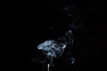 incense stick with smoke against black background