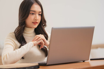 Asian girl using computer laptop playing game and social media or chatting with her friends.