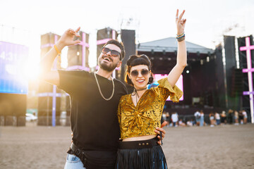 Young and cheerful couple at music festival. Happy friends drinking beer and having fun at Beach party together. Summer holiday, vacation concept.