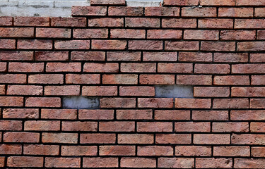 The Old Cracked Wall of a concrete building. A part of the red brick wall was abandoned.