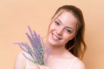 Young caucasian girl isolated on beige background holding a lavender plant. Close up portrait