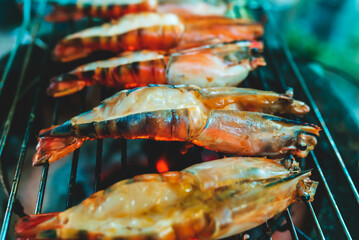 Large prawns are placed on an iron griddle and grilled over a hot coal stove.