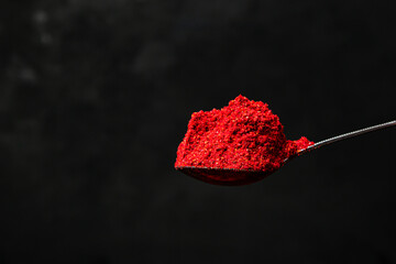 Spoon of ground red pepper on a black background. Hot red pepper. ground paprika
