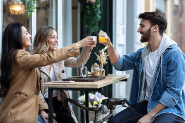 Group of cool friends sharing a brunch together while talking and looking the smartphone on the healthy coffee shop terrace.