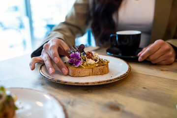 Close up of cool woman having healthy toast for breakfast in a healthy coffee shop.