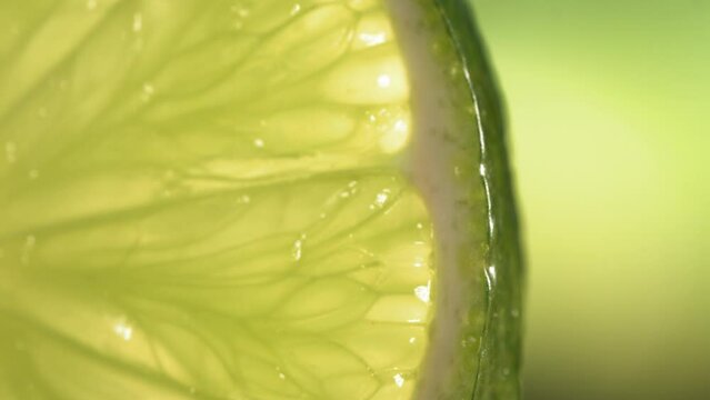 Drop of water flows down the surface of a ripe juicy Lime slice. Slow Motion 4K