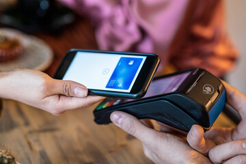 Customer using her credit card to make payment with electronic reader in the restaurant.