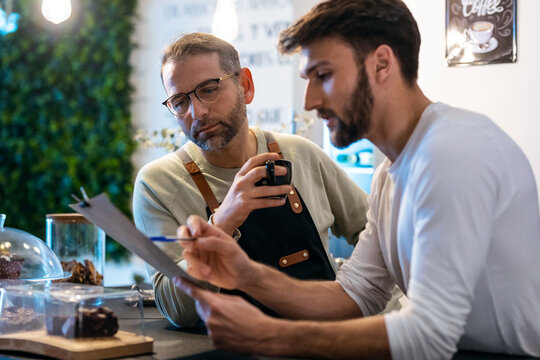 Couple owners bakery working while analyzing report for order delivery with digital tablet in a healthy pastry shop.