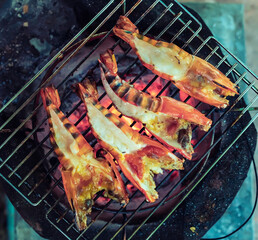 Large prawns are placed on an iron griddle and grilled over a hot coal stove.