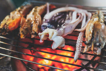 Grilled squid on a cast iron grill over a charcoal grill.