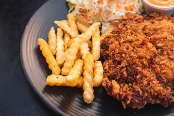 Pork batter with potato sticks and mayonnaise on a black plate