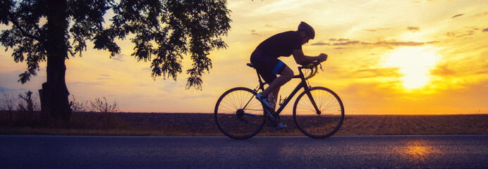 Young sports man biker cycling with bicycle on the road in summer - 514595615