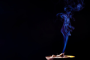 Closeup of smoke from burning incense stick on black background