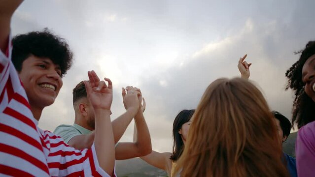 Group of friends having fun on the beach. Multiethnic Teenagers having a good time during the summer celebrating together next to the ocean.