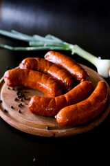 grilled sausage on a plate with vegetables. Sausages for grilling. Sausages board. Sausages on a black background. Tasty and juicy, natural grilled sausages.