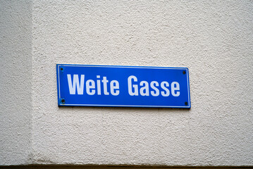 Road sign of alley with text Weite Gasse (German, translation is wide alley) at the old town of Zürich on a cloudy summer day. Photo taken June 28th, 2022, Zurich, Switzerland.