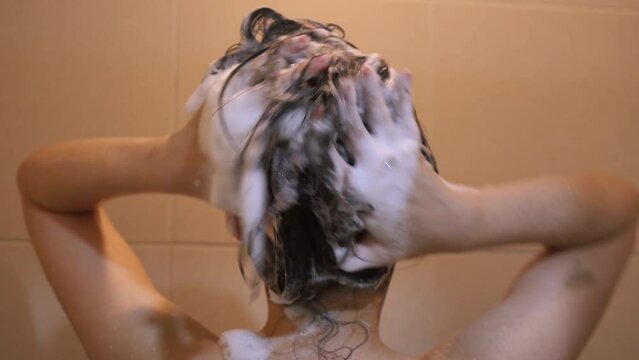 Asian girl washing her hair White foam from shampoo while bathing. Hair treatment, body cleaning in the bathroom
