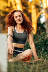 Young caucasian woman doing fitness stretching yoga exercise in the forest while using tablet for online class or virtual tutorials. healthy lifestyle.