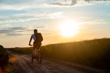 cyclist riding a bike at sunset. concept of extreme cycling. man driving bicycle on the way to the...