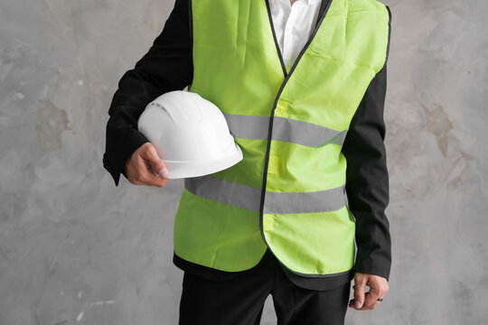 Close-up workwear and helmet in engineer or constructor hand as safety uniform with copy space on grey background