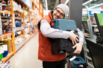 happy customer hugging a construction vacuum cleaner in a construction hypermarket