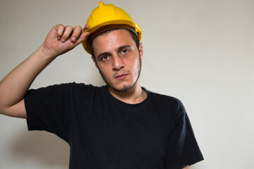 Worker with yellow safety hat for construction site work. Young white caucasian man with short hair and dark eyes.