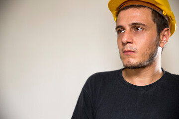 Worker with yellow safety hat for construction site work. Young white caucasian man with short hair and dark eyes.