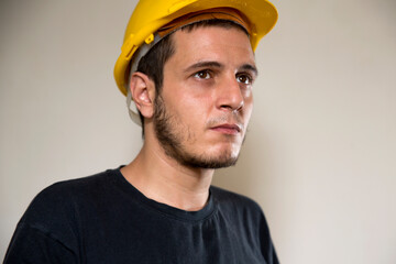 Worker with yellow safety hat for construction site work. Young white caucasian man with short hair...